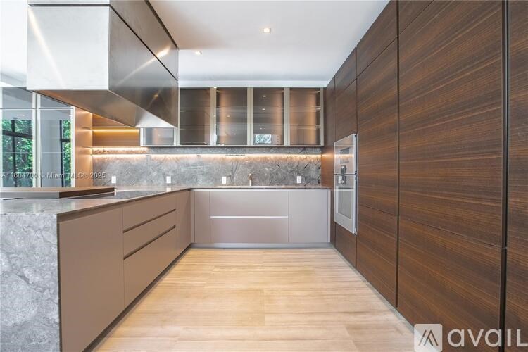 A modern kitchen with wooden cabinets and a marble countertop.