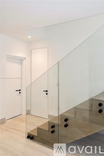 A hallway with a glass staircase and a white door.