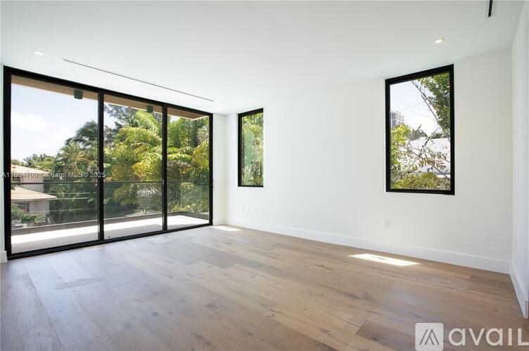 A spacious room with wooden flooring and sliding glass doors leading to a garden.