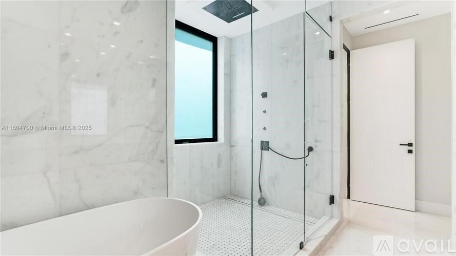 A modern bathroom with a glass shower enclosure and a white bathtub.