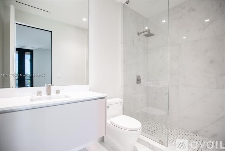 A white bathroom with a toilet, sink, and glass shower.