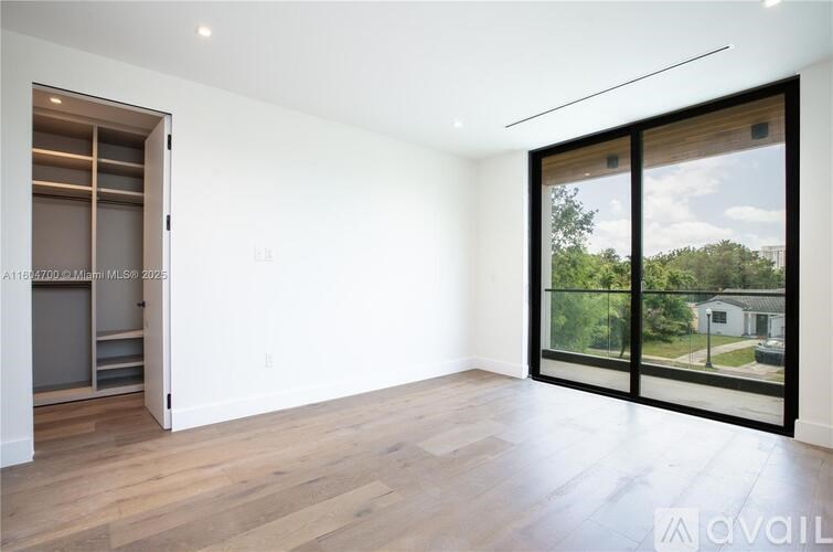 A large empty room with a sliding glass door leading to a backyard.
