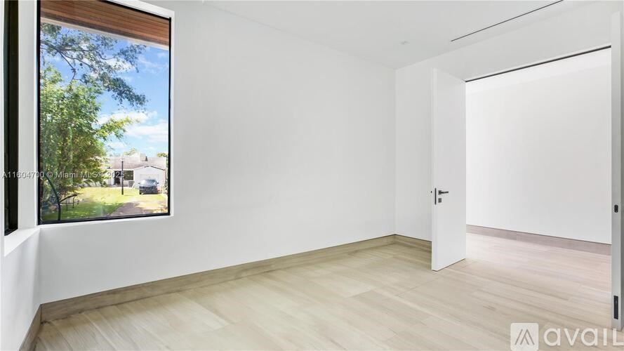 A room with a large window showing a view of a residential area.