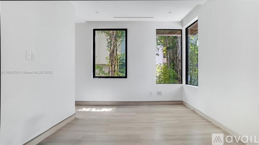 A spacious room with a large painting on the wall and a view of trees outside the window.
