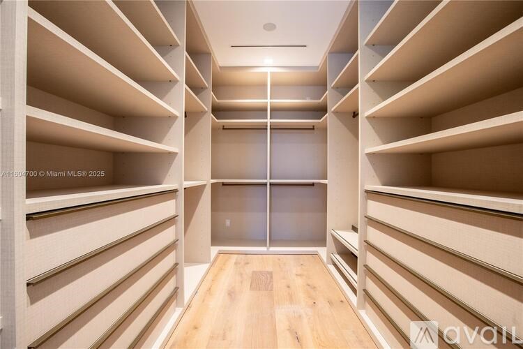A spacious walk-in closet with wooden shelves and a central mirror.