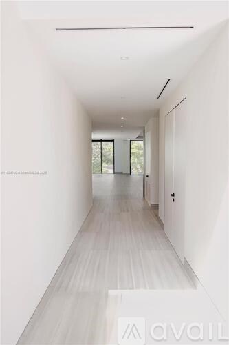 A long white hallway with a door at the end.