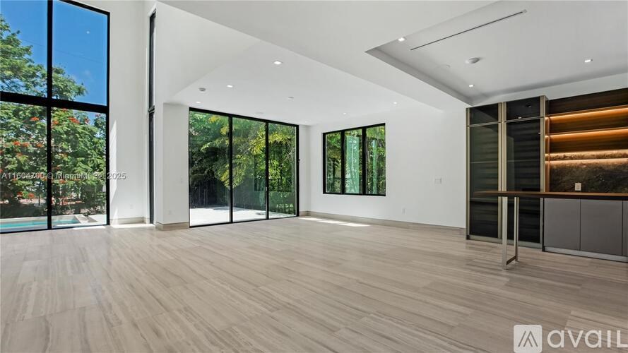 A spacious room with wooden flooring and large windows.