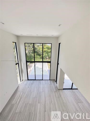 A room with a wooden floor and a glass door leading outside.