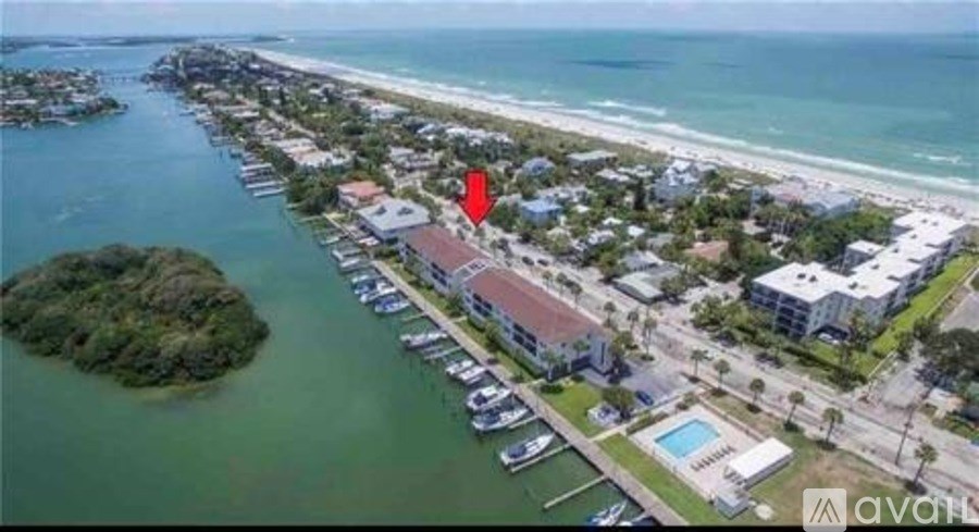 An aerial view of a coastal area with a red arrow pointing to a specific building.
