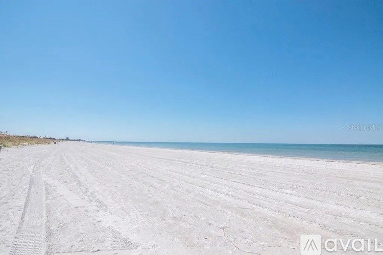 A beach with tire tracks in the sand.