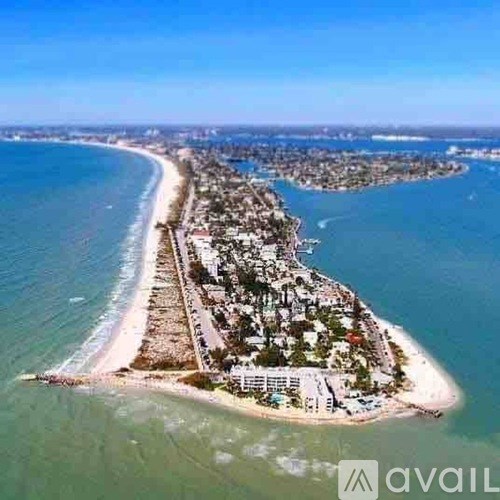 A small island with a beach and buildings is surrounded by water.