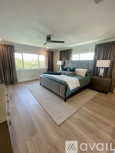 A bedroom with a large bed and a ceiling fan.