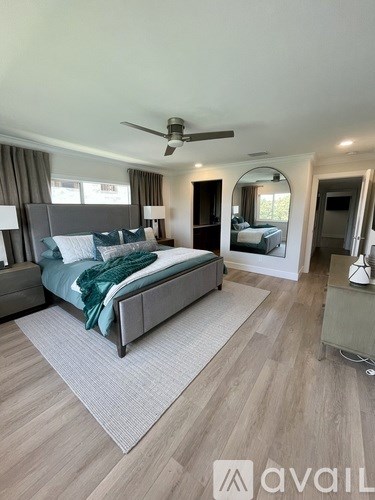 A bedroom with a large bed and a ceiling fan.