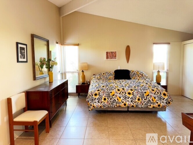 A bedroom with a patterned bed, a wooden chair, and a mirror on the wall.
