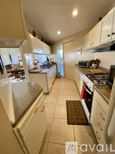 A kitchen with white cabinets and a tiled floor.