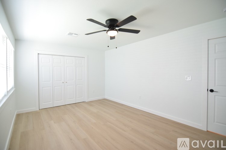 A room with a ceiling fan and wooden flooring.