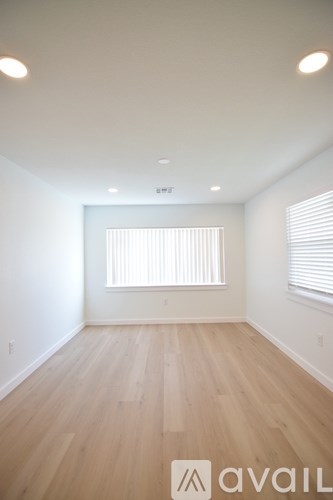 A room with wooden flooring and a window with blinds.