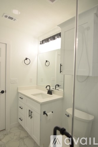 A bathroom with a sink, mirror, and toilet.