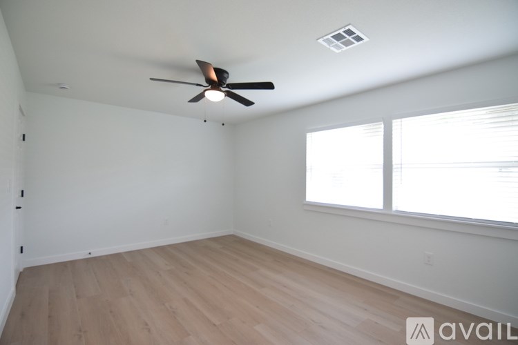 A room with a ceiling fan and wooden flooring.