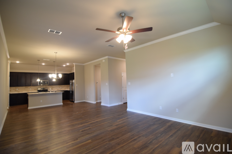 A spacious room with a ceiling fan and wooden flooring.