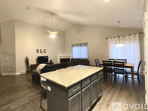 A spacious living room with a kitchen area and a dining table.