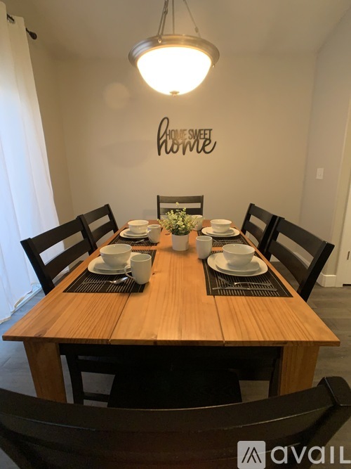 A wooden dining table with chairs and a wall decoration reading "home sweet home".