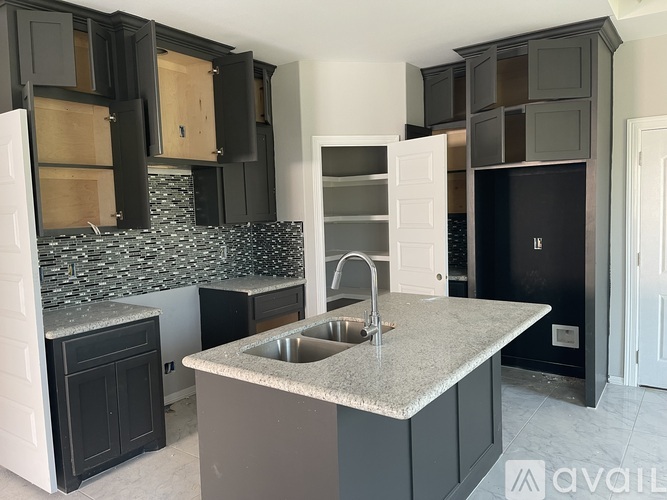 A kitchen with black cabinets and a granite countertop.