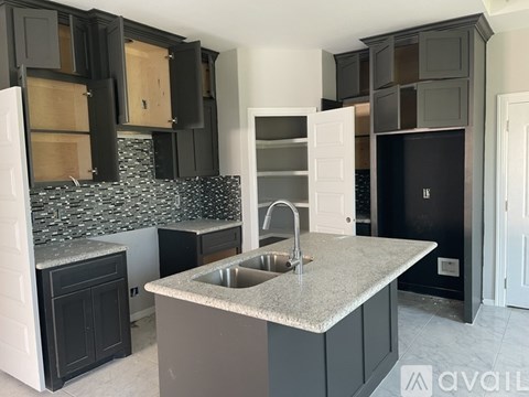 A kitchen with black cabinets and a granite countertop.
