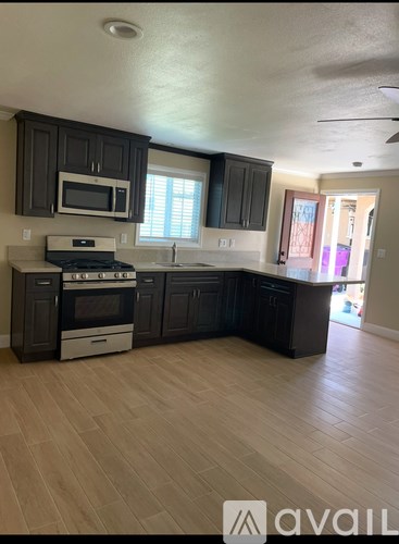 A kitchen with dark wood cabinets and a white stove top oven.