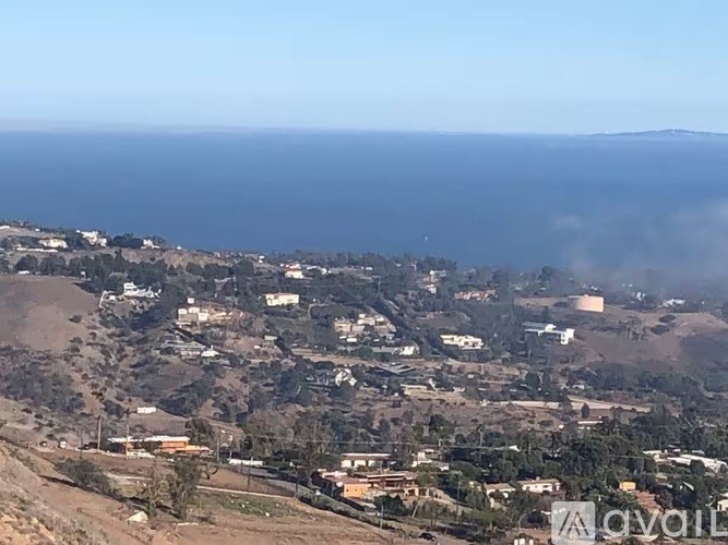 A coastal town with houses and buildings on a hillside.