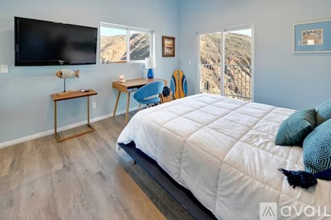A bedroom with a large bed and a flat screen TV mounted on the wall.