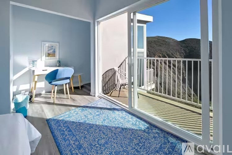 A balcony with a chair and table is visible from a living room.