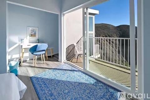 A balcony with a chair and table is visible from a living room.