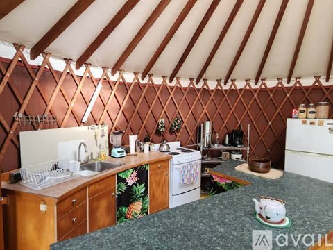 A kitchen with a sink, stove, and oven inside a yurt.