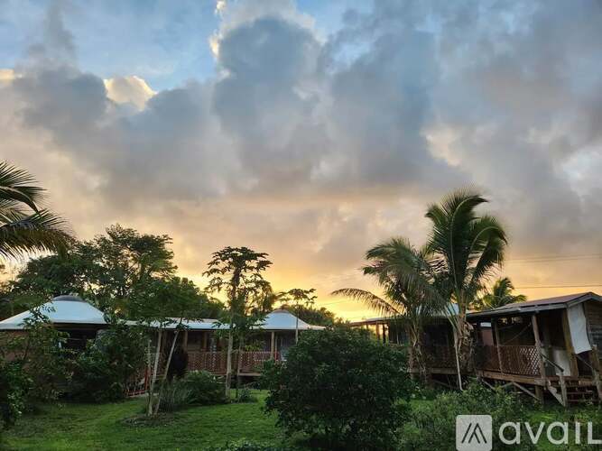A sunset view of a tropical resort with palm trees and bungalows.
