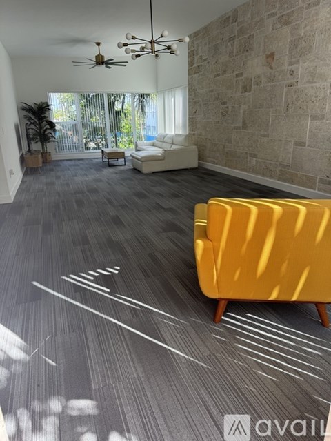 A living room with a yellow chair and a grey carpet.