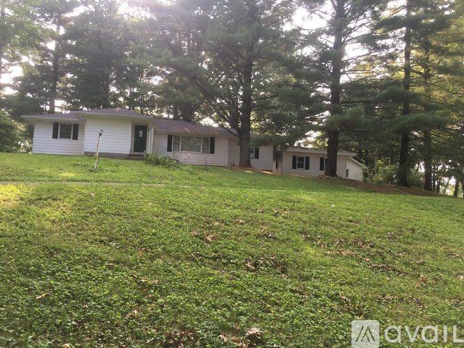 A house with a white exterior is surrounded by trees.