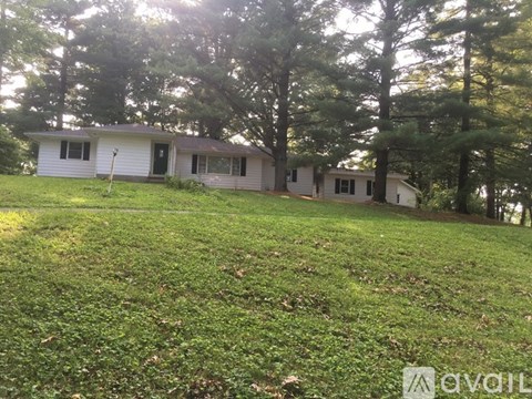 A house with a white exterior is surrounded by trees.