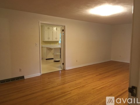 A room with wooden floors and a doorway leading to another room.