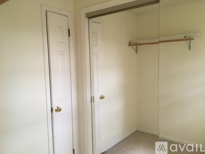 A room with two doors and a shelf above the closet door.