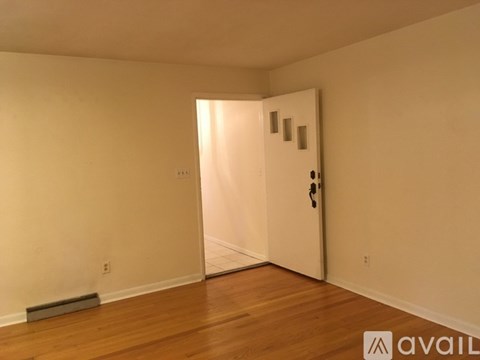A room with a white door and wooden floor.