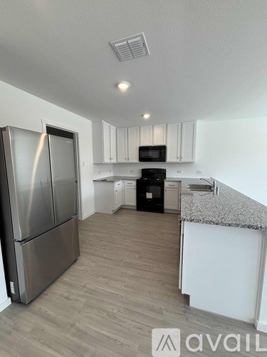 A kitchen with a refrigerator, microwave, oven, and cabinets.