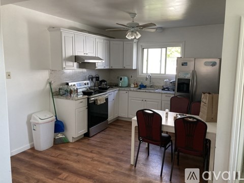 A kitchen with white cabinets and a wooden floor.