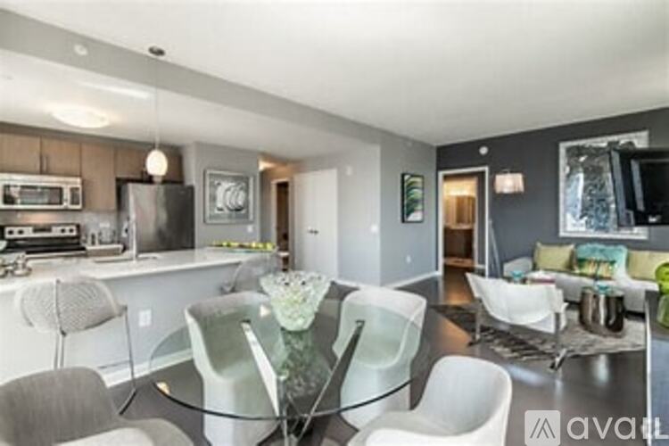 A modern kitchen with a glass table and white chairs.