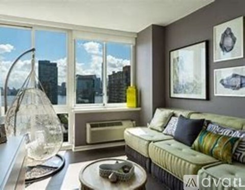 A living room with a green couch and a large window overlooking a city.