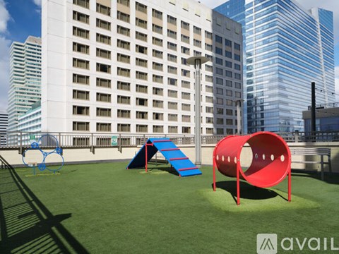 A playground with a red tunnel and a blue slide in front of a white building.