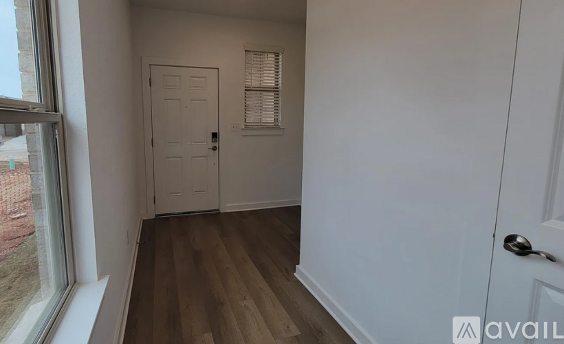 A room with a white door and a window with a view of a construction site.