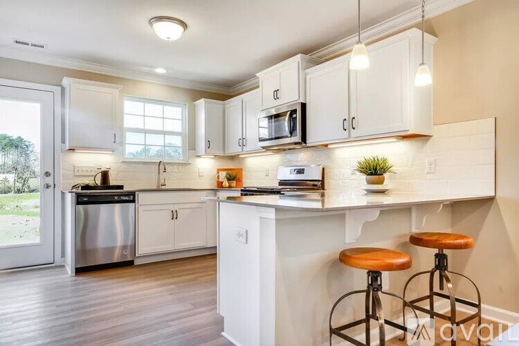 A kitchen with white cabinets and a white island with two stools.