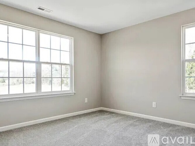 A room with two windows and carpeted floor.