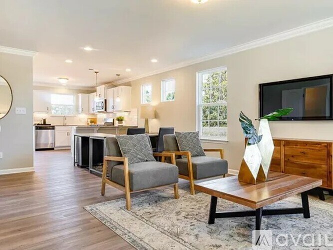 A living room with a grey couch, a wooden coffee table, and a television on the wall.